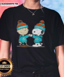 Alt Text: Charlie Brown and Snoopy fist bump in Miami Dolphins football ladies tee, featuring vibrant graphics and playful design.