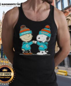Charlie Brown fist bumping Snoopy on a Miami Dolphins tank top featuring Nice Peanuts design.