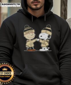 Charlie Brown and Snoopy fist bump in a New Orleans Saints hoodie, celebrating friendship and football spirit.