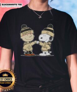 Charlie Brown and Snoopy fist bump in New Orleans Saints football ladies tee, celebrating Peanuts fandom and team spirit.