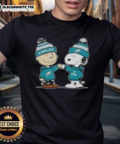Charlie Brown and Snoopy fist bump on a Philadelphia Eagles football t-shirt, celebrating team spirit and friendship.