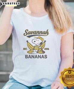 Alt Text: Snoopy lying on a banana, wearing a Savannah Bananas outfit, featured on a ladies tee from Est. 2016.