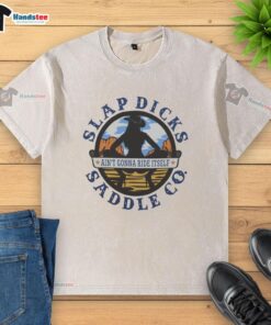 Alt Text: Official Ain't Gonna Ride Itself Slap Dicks Saddle Co Logo on a washed t-shirt, perfect for casual wear.