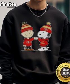 Charlie Brown and Snoopy fist bump on a San Francisco 49ers football sweatshirt, perfect for Peanuts fans.