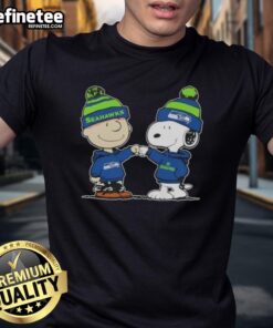 Alt Text: Official Peanuts Charlie Brown fist bump with Snoopy on Seattle Seahawks football T-shirt, perfect for fans.