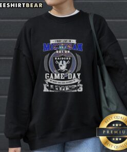 Alt Text: Michigan fan wearing Las Vegas Raiders football sweatshirt, showcasing team spirit on game day.