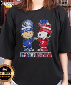 Alt Text: Pretty Charlie Brown fist bump with Snoopy, featuring Philadelphia City Sports 76ers x Phillies ladies tee design.