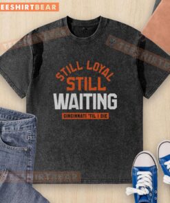 Pretty Still Loyal Still Waiting Cincinnati 'Til I Die washed t-shirt displayed on a wooden surface, showcasing vibrant design.