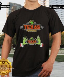 Top Grinch hands holding a Texas Roadhouse Merry Christmas T-Shirt, perfect for festive holiday celebrations.