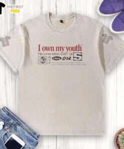 Top I Own My Youth No One Else Cans washed t-shirt displayed on a hanger, showcasing a trendy design for casual wear.