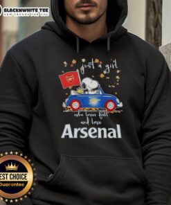 Alt Text: Snoopy driving a car, wearing a hoodie that says Just a girl who loves fall and Arsenal FC with autumn leaves.