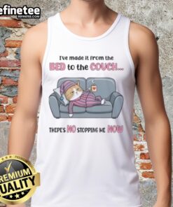 Top tired cat relaxing on a couch after moving from the bed, showcasing its playful spirit in a tank top.