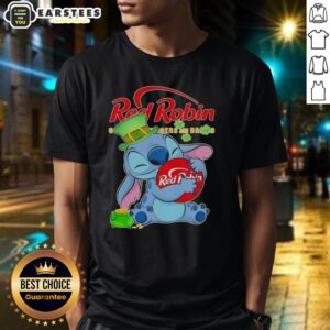 Cute Stitch hugging a red robin logo on a Happy Patrick's Day T-shirt, perfect for festive celebrations.