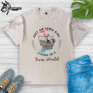 Alt Text: Top Just An Iowa Girl Living In A Texas World washed t-shirt displayed on a rustic wooden background.