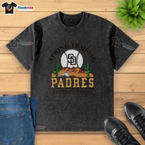 Alt Text: Premium San Diego Padres Cactus League Desert Washed T-Shirt displayed on a wooden background, showcasing its soft fabric and logo.