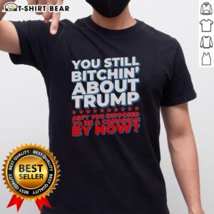 Alt Text: Official 'You Still Bitchin About Trump AinT You Supposed To Be A Canadian By Now' T-Shirt design featuring bold text.