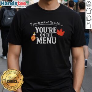 Alt Text: Original If You're Not At The Table, You're On The Menu T-Shirt design featuring bold typography on a casual tee.
