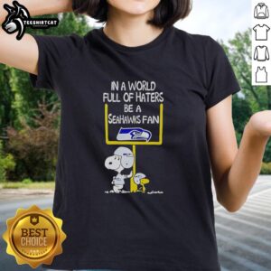 Premium Snoopy tee for ladies featuring 'In a World Full of Haters, Be a Seahawks Fan' design, perfect for Seahawks supporters.