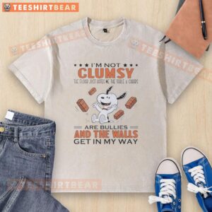 Alt Text: Funny Snoopy t-shirt featuring 'I'm not clumsy, the floor just hates me' with a table and chairs design.