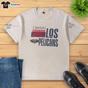 Alt Text: Official Noches Ene Be A Somos Los New Orleans Pelicans washed t-shirt featuring team logo and vibrant colors.