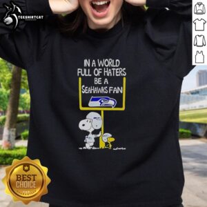 Premium Snoopy sweatshirt with 'In a World Full of Haters, Be a Seahawks Fan' design, perfect for Seattle Seahawks supporters.
