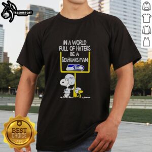 Premium Snoopy T-Shirt: 'In A World Full Of Haters Be A Seahawks Fan' featuring Snoopy in Seahawks colors.