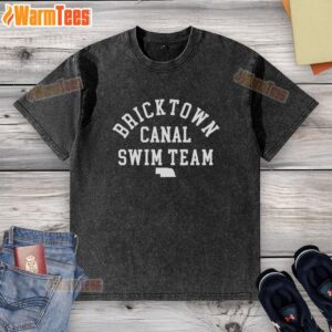 Nice Bricktown Canal Swim Team Nebraska washed t-shirt displayed on a wooden surface, showcasing vibrant colors and design.