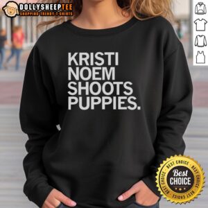 Kristi Noem wearing a sweatshirt while playfully shooting puppies outdoors, showcasing her love for animals and casual style.