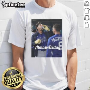 Alt Text: Jac Caglianone of the Kansas City Royals enjoying espresso in the dugout, wearing an Almost Friday T-shirt.