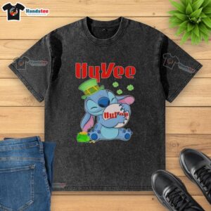 Alt Text: Cute Stitch hugging Hy-Vee logo on a St. Patrick's Day washed t-shirt, perfect for festive celebrations.