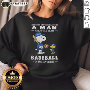 Alt Text: Cute Peanuts X Texas Rangers sweatshirt featuring 'Never Underestimate A Man Who Still Plays Baseball In His Seventies' design.