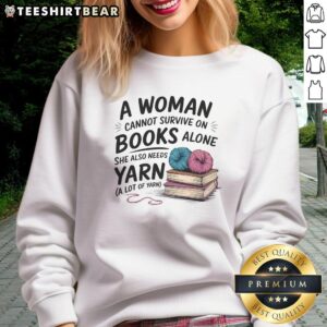 Alt Text: Woman wearing 'A Woman Cannot Survive On Books Alone She Also Needs Yarn' sweatshirt, showcasing a cozy reading and crafting vibe.