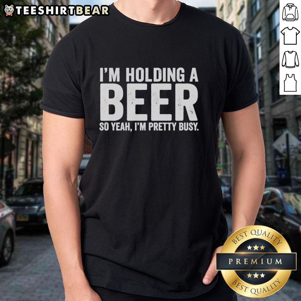 awesome-im-holding-a-beer-so-year-im-pretty-busy-t-shirt-1 Alt Text: Awesome I'M Holding A Beer So Year I'M Pretty Busy T-Shirt featuring a fun graphic design and casual style.
