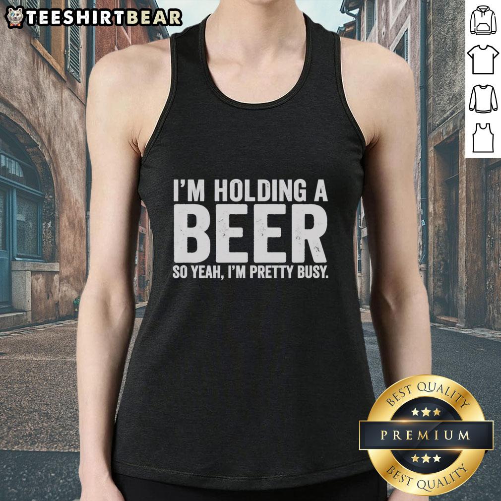 awesome-im-holding-a-beer-so-year-im-pretty-busy-tank-top Person wearing an 'Awesome I'm Holding A Beer So Year I'm Pretty Busy' tank top, enjoying drinks at a sunny outdoor gathering.