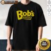 Alt Text: Official Trey Anastasio Bob's Surplus logo t-shirt featuring a vibrant design, perfect for fans and collectors.