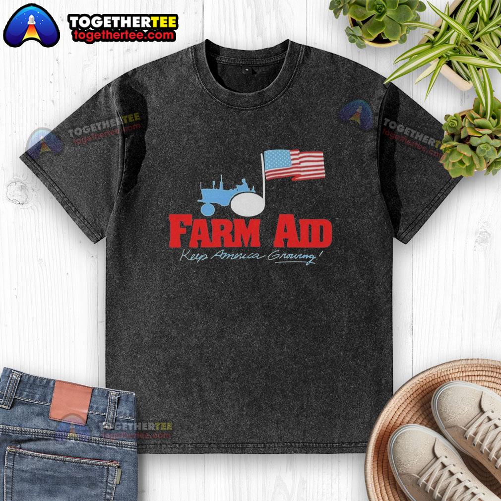 Premium Farm Aid Keep America Growing The Logo Of A Tractor And The American Flag Washed T-Shirt Alt Text: Premium Farm Aid Keep America Growing logo featuring a tractor and American flag on a washed t-shirt.