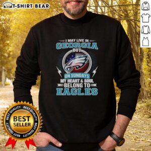 Alt Text: Official Philadelphia Eagles sweatshirt with I May Live in Georgia, But My Heart Belongs to Eagles slogan.