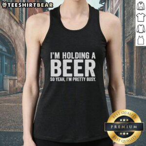 Person wearing an 'Awesome I'm Holding A Beer So Year I'm Pretty Busy' tank top, enjoying drinks at a sunny outdoor gathering.
