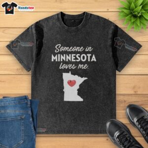Premium 'Someone in Minnesota Loves Me' washed t-shirt displayed on a wooden background, showcasing its soft fabric and vibrant print.