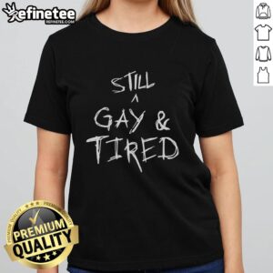 Alt Text: Handwritten text on a 'Still A Gay And Tired' tee shirt for Pride, showcasing vibrant colors and a bold statement.