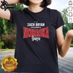 Zach Bryan performing live in concert at Nebraska Huskers, wearing a stylish ladies tee, captivating the audience.