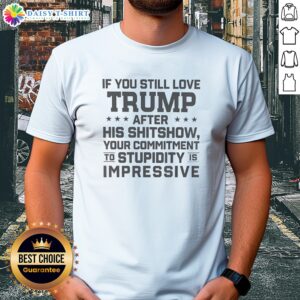 Pretty Trump Commitment To Stupidity Is Impressive Text Still Love After His Shitshow Shirt displayed on a flat lay background.
