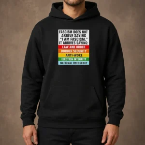 Original Fascism Does Not Arrive Saying I Am Fascism It Arrives Saying Law And Order Hoodie in dark color with front pocket and hood