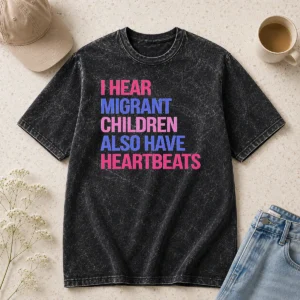 Good I Hear Migrant Children Also Have Heartbeats Bold Statement Text printed on a soft washed t shirt in light gray