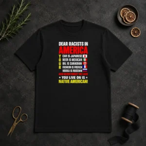 Official Dear Racists In America You Live On Is Native American t shirt in black, front view with clear bold white text