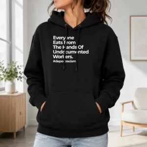 Good Funny Everyone Eats From The Hands Of Undocumented Workers Deport Racism Statement Hoodie in black, front view with bold white text