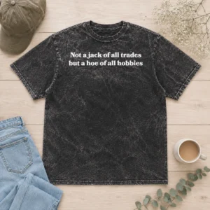 Top Not A Jack Of All Trades But A Hoe Of All Hobbies washed t shirt in soft cotton fabric, laid flat showing front print