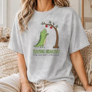 Good T Rex Eating Healthy The Ancient Struggle printed on a soft washed t shirt in light gray